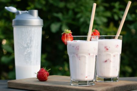 protein-shake-from-yogurt-and-strawberries-in-a-shaker-and-two-glass-glasses-on-a-wooden-table